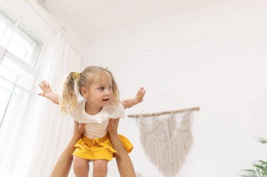 Babası küçük kızıyla oynuyor, onu kollarına alıyor. Babası kızını kollarında tutuyor..