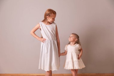 Kız kardeşler birbirlerine bakıyorlar. Kızlar el ele tutuşur