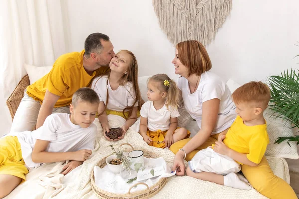 Family of five and their cat having breakfast in their bed in the morning