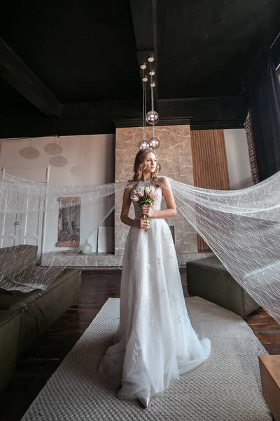 a lot of veil . bride in fancy dress. wedding dress with long arms. dark interior