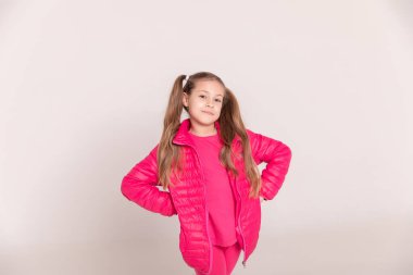 Beyaz arka planda kuyruğu olan bir kız. Pembe ceketli bebek. Boşluğu kopyala