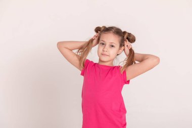 Beyaz arka planda mutlu bir çocuk. Pembe tişörtlü ve pantolonlu bir kız. Kuyruklu kız. Boşluğu kopyala