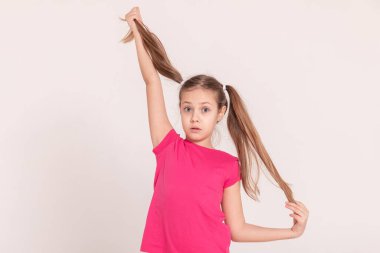 Beyaz arka planda mutlu bir çocuk. Pembe tişörtlü ve pantolonlu bir kız. Kuyruklu kız. Boşluğu kopyala