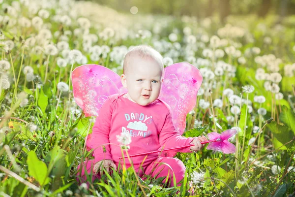 Barn med vingar bland maskrosor — Stockfoto