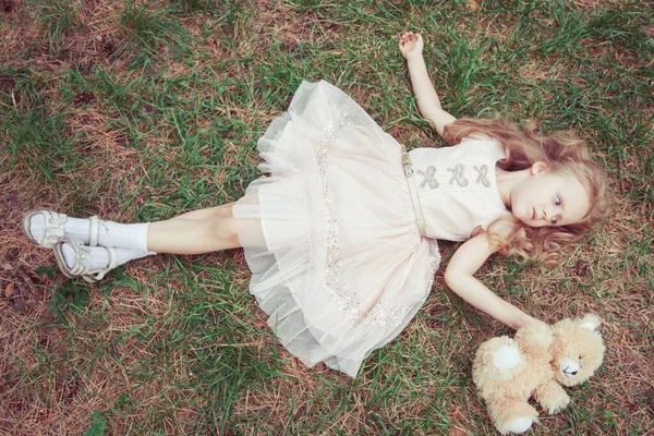 Doce Menina Deitada Grama Parque Com Seu Urso Brinquedo — Fotografia de Stock