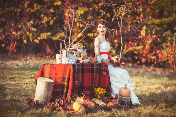 Braut sitzt im Herbstwald am Tisch — Stockfoto
