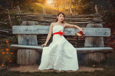 Gelin bir eski tahta bankta oturur