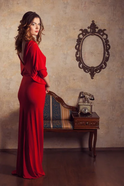 Menina vestindo um vestido vermelho em pé na sala retro — Fotografia de Stock