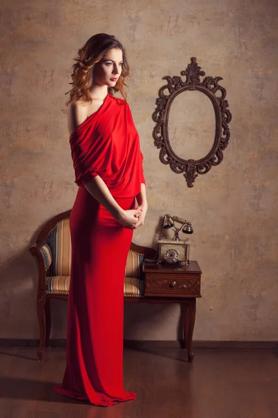Vacker flicka i röd klänning står och tittar ner — Stockfoto