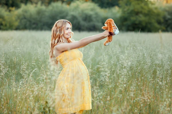 Schwangere auf dem Feld, Spielzeug vor sich haltend — Stockfoto