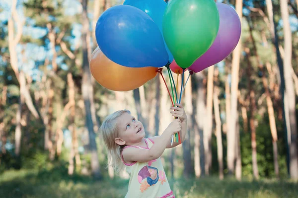 Mädchen mit einer Armvoll Luftballons — Stockfoto