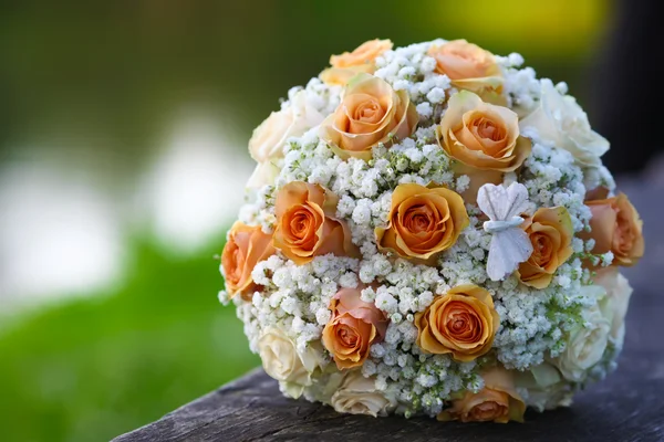 Wedding bridal bouquet of orange roses lying on wooden floor — Stock Photo, Image