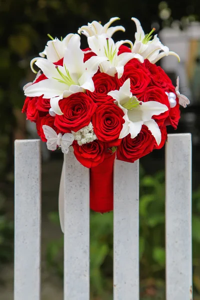 Ramo de novia de boda con rosas rojas y lirios en la valla —  Fotos de Stock