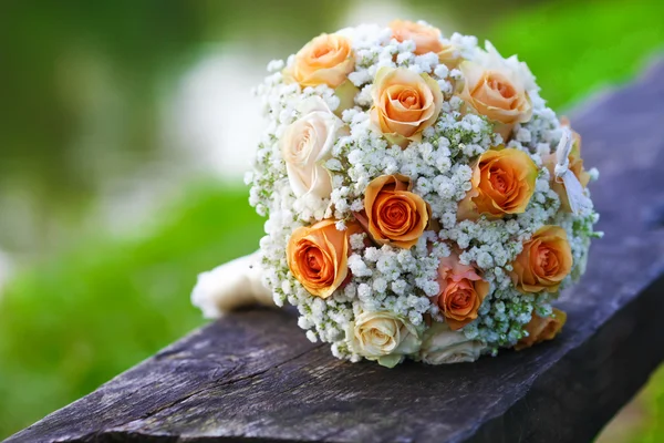 Ramo nupcial de rosas naranjas tumbadas en el suelo de madera — Foto de Stock