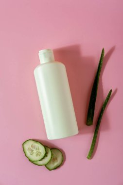 Aloe vera ve pembe arka planda salatalıklı kozmetik ürünleri. Mesaj için yer var. Düz konum