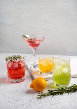 Beyaz masada gözlüklü dört renkli yaz kokteyli. Taze yaz içecekleri. Pembe ve kırmızı sangria kokteylleri, portakal kokteyli, margarita kokteyli, tropikal katır..