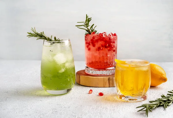 Three colorful summer cocktails in glasses on  white table. Assortment of fresh  summer drinks. Red sangria cocktails, orange punch cocktail, margarita cocktail, tropical mule.