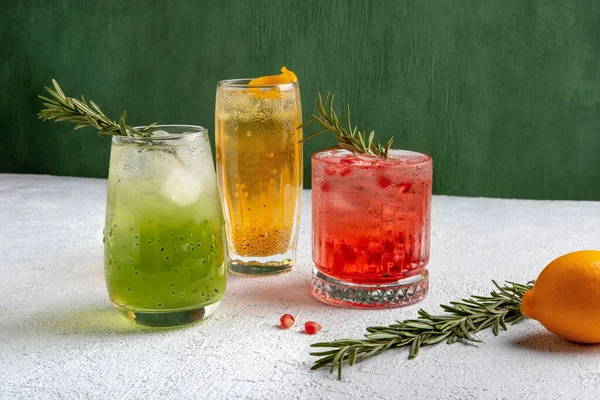 Three colorful summer cocktails in glasses on  grey table. Assortment of fresh  summer drinks. Red sangria cocktails, orange punch cocktail, margarita cocktail, tropical mule.