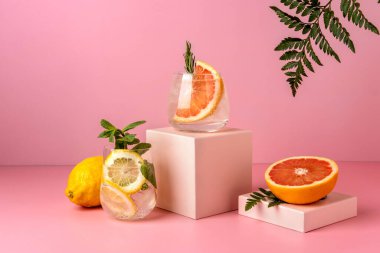 Greyfurt ve limonlu iki sert maden suyu kokteyli. Renkli yaz içkileri pembe arka planda gölge eğreltiotu ile ferahlatıcı. 