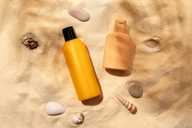 Kumsalda bir şişe güneş kremi. Cilt bakımı ve koruma konsepti. Altın ten..