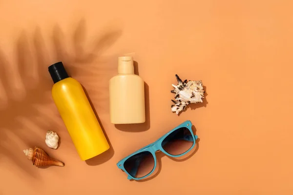 Bottle of sunscreen lotion on a beige background with shadows from tropical leaves. Skin care and protection concept. Golden tan. Flat lay