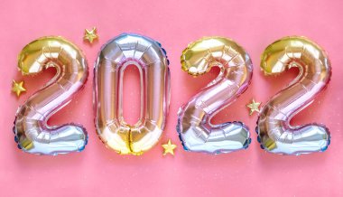 Yeni yıl 2022 kutlaması. Folyo balonları numarası 2022 ve pembe arka planda Parıldayan Yıldızlar. Düz yatıyordu