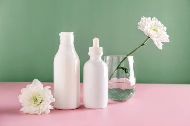 Doğal kozmetik ürünlerini taklit et: serum, krem, yeşil arka planda çiçekli reklamlar için maske. Organik ürünler. Spa konsepti