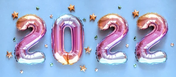 Yeni yıl 2022 kutlaması. Folyo balonları numarası 2022 ve mavi arka planda Parıldayan Yıldızlar. Düz yatıyordu