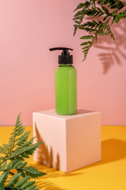 Çiçekli sarı ve pembe arka planda kozmetik ürünleri için yaz gösterisi. Yeşil şişe kozmetik ürünü pembe podyumda
