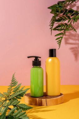 Kozmetik ürünleri sergisi için sarı arka planda yaz gösterisi. Ahşap bir kürsüde yeşil ve sarı kozmetik ürünleri.