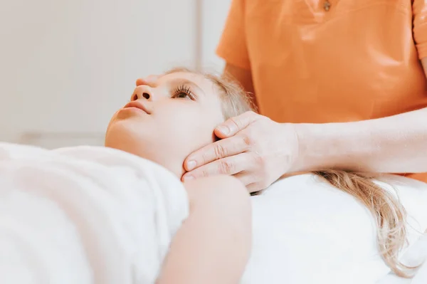 real doctor osteopath hands does physiological and emotional therapy for eight year old kid girl. pediatric osteopathy treatment session. alternative medicine. taking care of the child\'s health