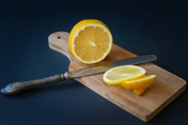 Koyu bir arka plan değil, olgun dilimlenmiş limon, çay ve bal kesme tahtasında..