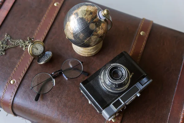 Still life with vintage objects. A step-by-step chmodan, a camera, a globe, books and a clock.