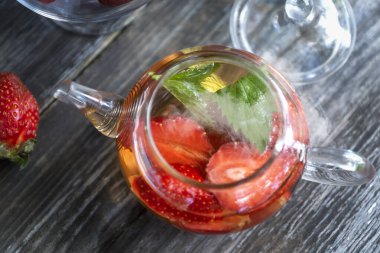 Yaz bahçesinde çilek ve nane yapraklı meyveli kırmızı çay..