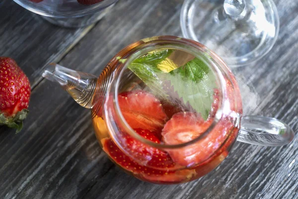 Yaz bahçesinde çilek ve nane yapraklı meyveli kırmızı çay..