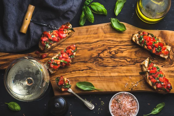 Rajče a bazalka bruschettas s sklenku bílého vína — Stock fotografie