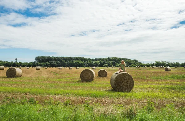 Young blond girl sitting on haystack