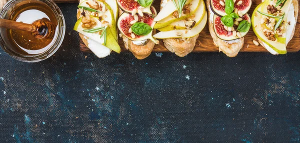 Crostini with pear, ricotta cheese, honey, figs, nuts and herbs — Stock Photo, Image