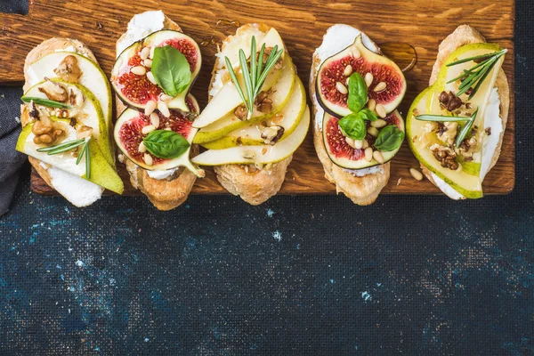 Crostini com pêra, queijo ricota, figos, nozes e ervas frescas — Fotografia de Stock