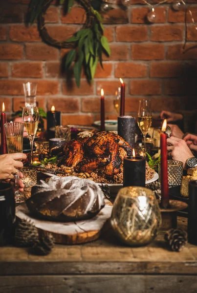 圣诞或新年庆祝会桌上布置 一家人与烤火的土耳其一起坐在节日桌旁 有米饭和栗子 面包蛋糕 蜡烛和香槟 砖墙背景 — 图库照片