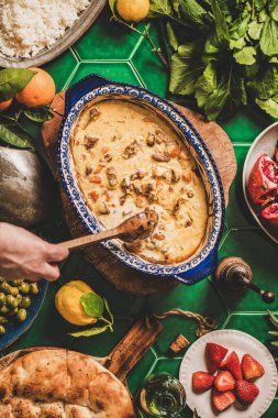 Türk usulü aile yemeği. Yoğurt soslu Türk kuzusunu pirinç pilavı, taze roka ve çilekli salata ile karıştıran kadın eli. Ramazan iftar yemeği