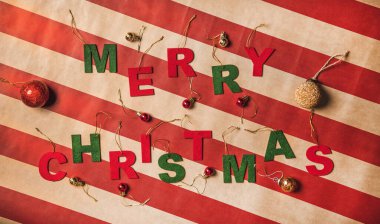 Süslü kırmızı ve yeşil harflerle süslenmiş mutlu noel sözcüklerinin düzleştirilmiş hali, kaliteli çizgili ambalaj kağıdı, üst görünüm. Noel bayramı bayrak konsepti
