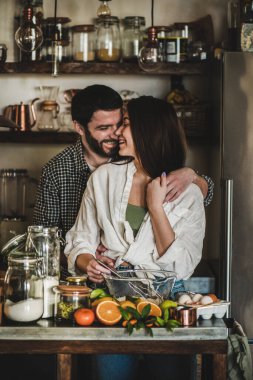 Genç çift mutfakta birlikte yemek pişiriyor.