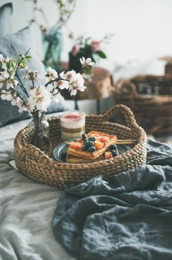 Waffle ve gül latte ile yatakta kahvaltı