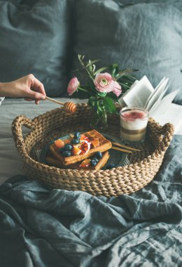 Kan portakalı ve yaban mersinli waffle, cam içinde gül latte ve çiselemeli el.