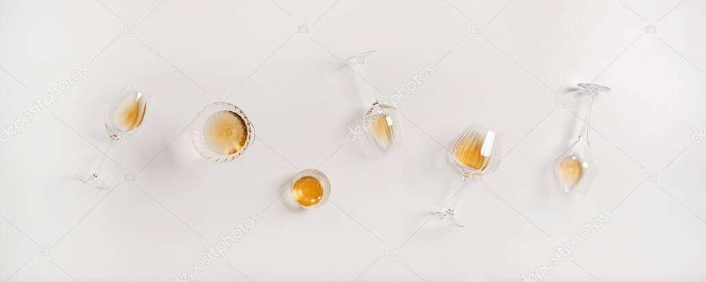 Flat-lay of trendy Orange or Amber wine in different glasses over plain white background, top view. Skin contact, skin macaration, wine tasting, wine shop, wine bar, winery concept