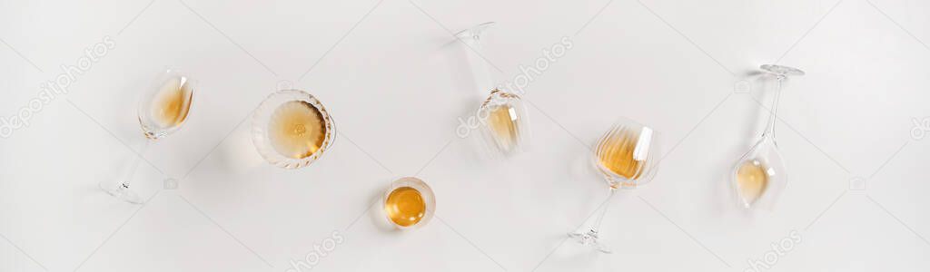 Flat-lay of trendy Orange Amber wine in different glasses over plain white background, top view, wide composition. Skin contact, skin macaration, wine tasting, wine shop, wine bar, winery concept