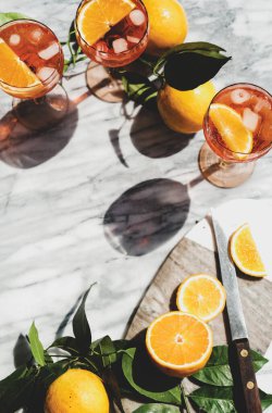 Portakallı ve buzlu bardaklarda Aperol Spritz aperatifi. Gri mermer masa, üst manzara, fotokopi alanı. Yaz ferahlatıcı içecek konsepti