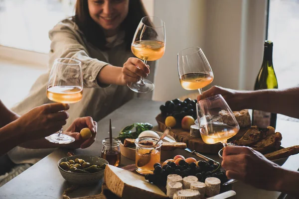 様々なグルメスナックチーズブドウパンとテーブルの上の人々の友人の手に白いオレンジやバラのワインのメガネ ワインの試飲会のコンセプト — ストック写真