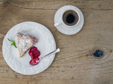 Ahududu cheesecake ve bir fincan kahve bir tahta üzerinde bir parça 